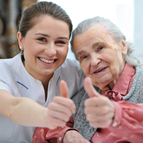 caregiver and senior woman giving thumbs up