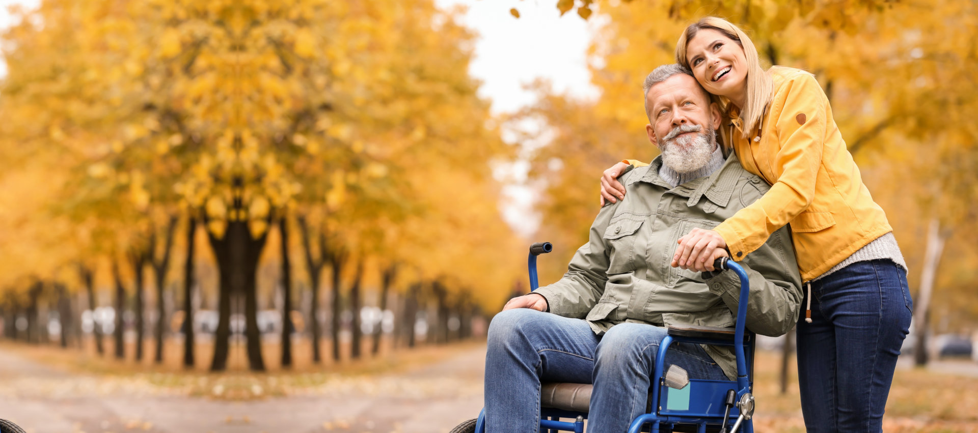 senior man in wheelchair with young woman outdoors