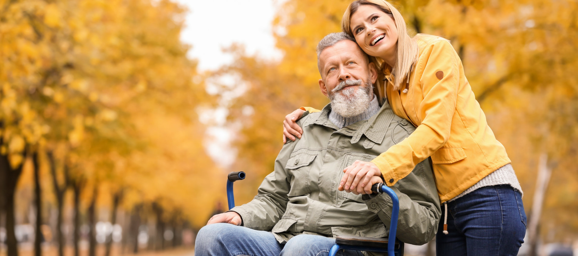 senior man in wheelchair with young woman outdoors