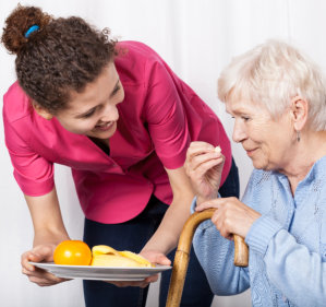 caregiver serving healthy foods to elderly woman