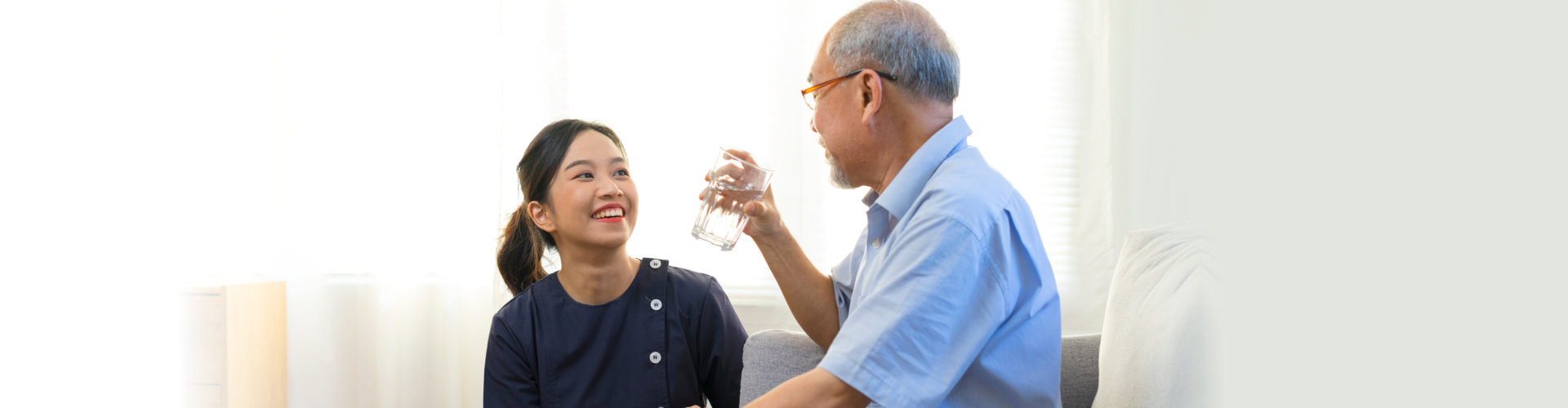 Smiling nurse giving glass of water to senior man